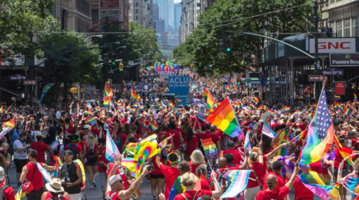many people waving pride flags in New York City street for Pride celebration